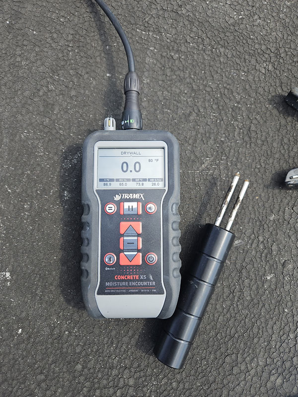 Tramex CMEX5 digital moisture meter with two-pin probe taking a reading on the modified bitumen roof at 2105 Mt Vernon Ave