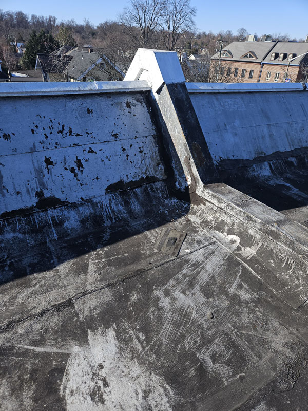 Weathered black modified bitumen roof and deteriorated parapet wall at 2105 Mt Vernon Ave in Alexandria, Virginia, before silicone restoration