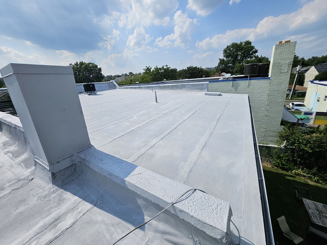 Primed roof field, parapet walls, and curb details at 2105 Mt Vernon Ave after PM P-160 bleed-block primer application