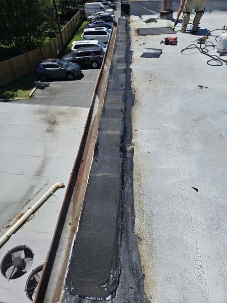 Rebuilt gutter line at 2330 Columbia Pike with new modified bitumen laid in along the reconstructed roof edge beside the weathered field