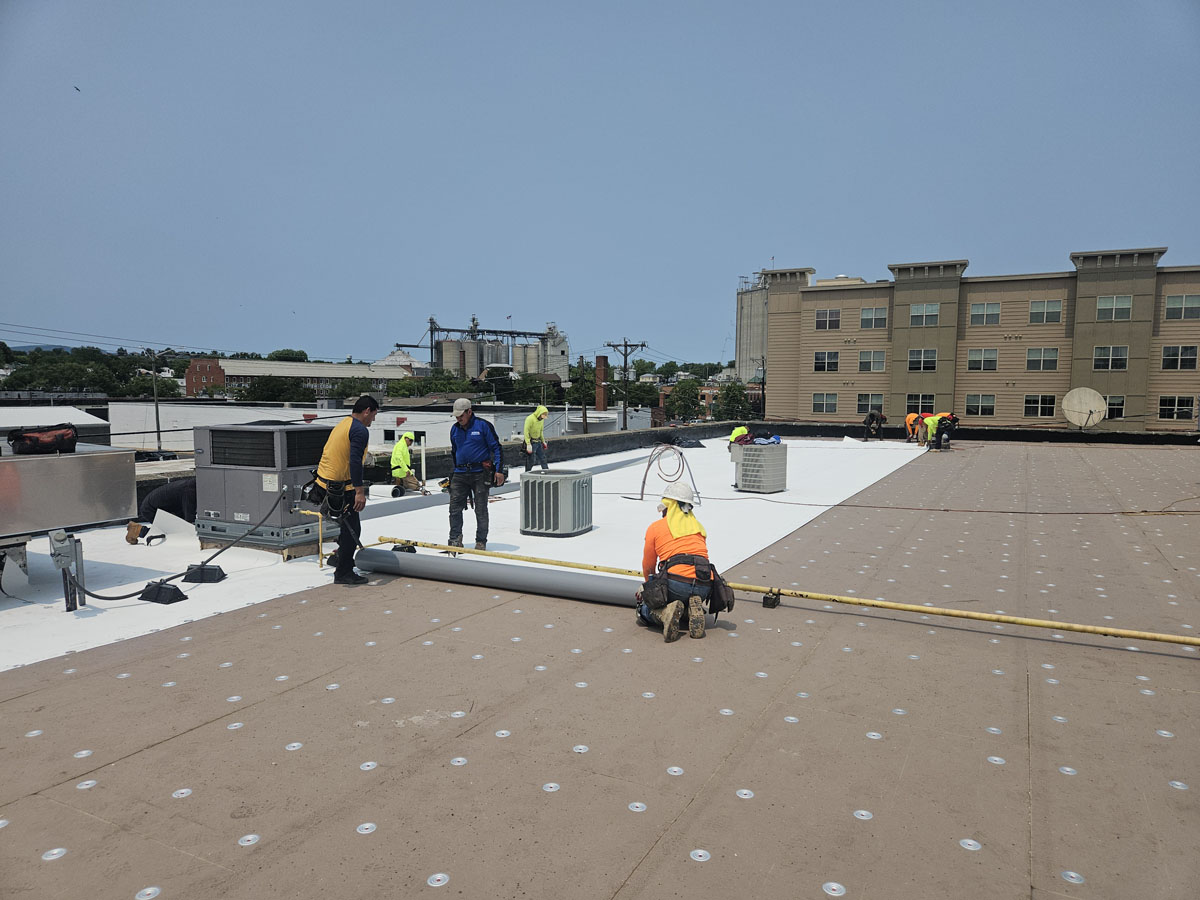 R-20 polyisocyanurate insulation board being installed over the exposed concrete roof deck at 150 E Wolfe St