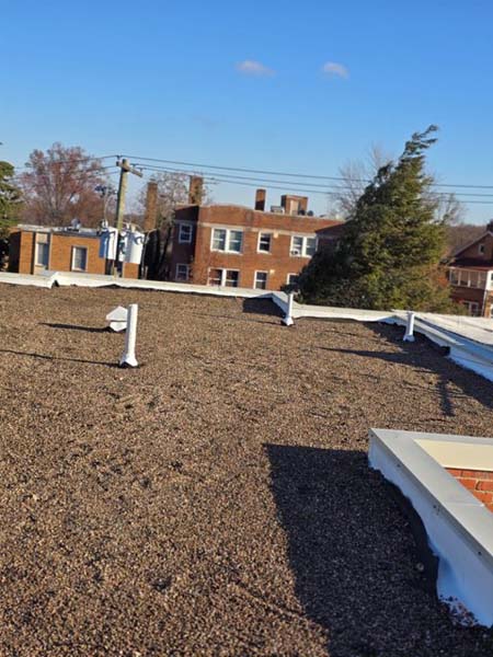 Completed TPO roof at 2801 Pennsylvania Ave SE with stone ballast reinstated over the new membrane and new white coping at the parapet