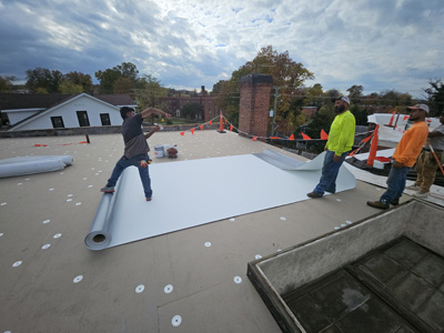 Crew rolling out Elevate UltraPly 60-mil TPO membrane over insulation board with fastening plates visible at 2801 Pennsylvania Ave SE