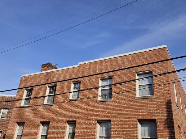 New parapet coping seen from grade along the brick elevation of the apartment building at 2801 Pennsylvania Ave SE