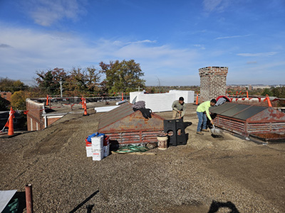 Crew clearing stone ballast from the modified bitumen roof at 2801 Pennsylvania Ave SE in preparation for tear-off