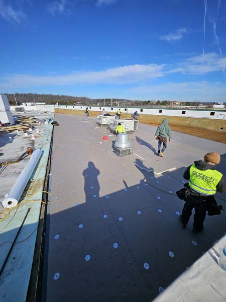 R-20 polyisocyanurate insulation board being installed over the exposed metal roof deck at 7171 New Market Ct
