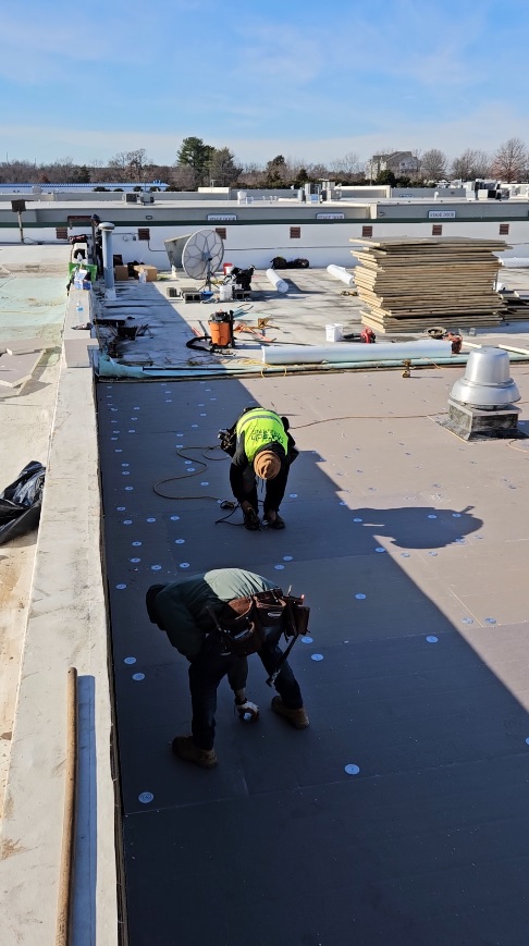 Polyisocyanurate insulation boards being laid across the metal roof deck at 7171 New Market Ct
