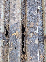 Severely rusted W-type metal roof deck exposed during tear-off at 7171 New Market Ct